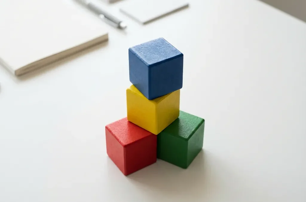 Vier gekleurde houten blokken gestapeld in piramide met rood, geel, groen en blauw DISC-kleuren op wit bureau