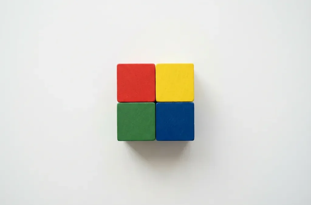 Vier gekleurde houten blokken in DISC-kleuren rood, geel, groen en blauw gerangschikt in vierkant op wit bureau