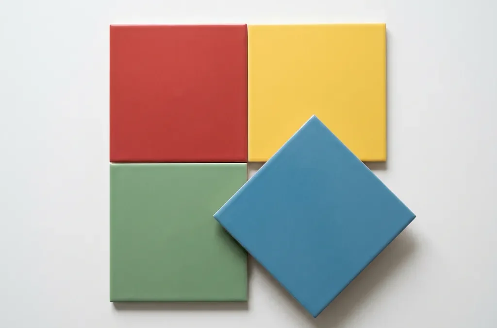 Vier gekleurde geometrische tegels in rood, geel, groen en blauw in een 2x2 raster, één tegel licht opgetild en gedraaid.